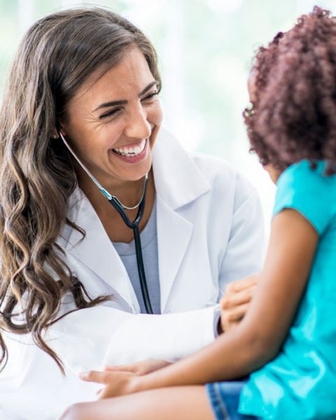 A smiling doctor cares for a young child after reading their translated medical records.