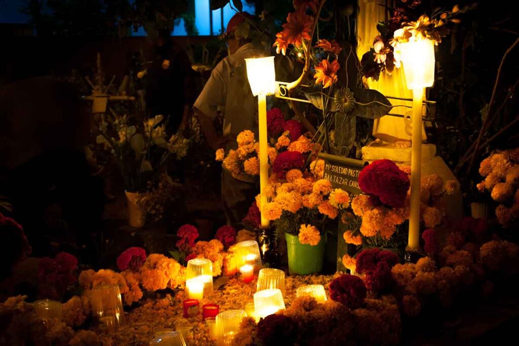 An offrenda, complete with candles and marigolds, adorns the grave during a celebration of Dia de los Muertos.