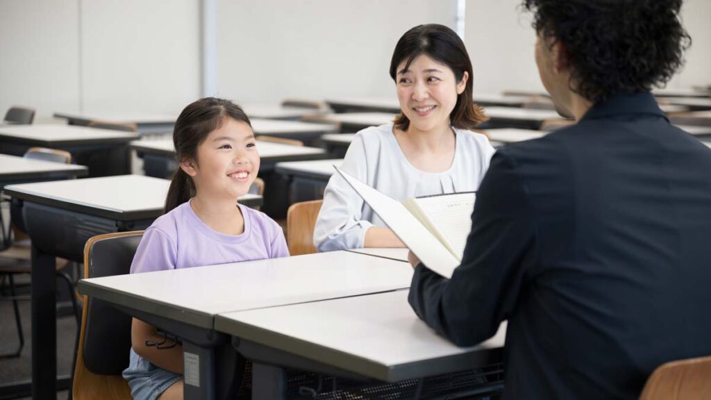 A parent looks at their child with pride at a parent-teacher conference.