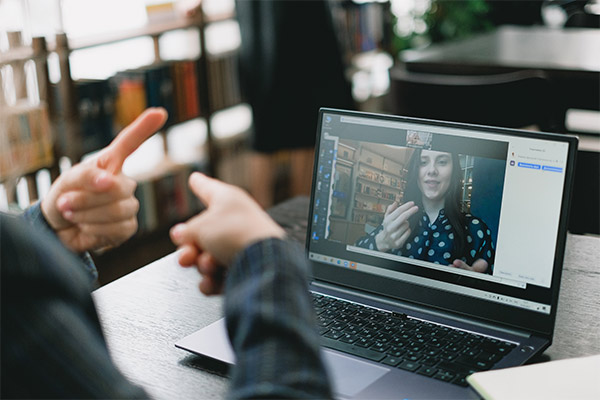 Two people on a video call signing to each other in American Sign Language.