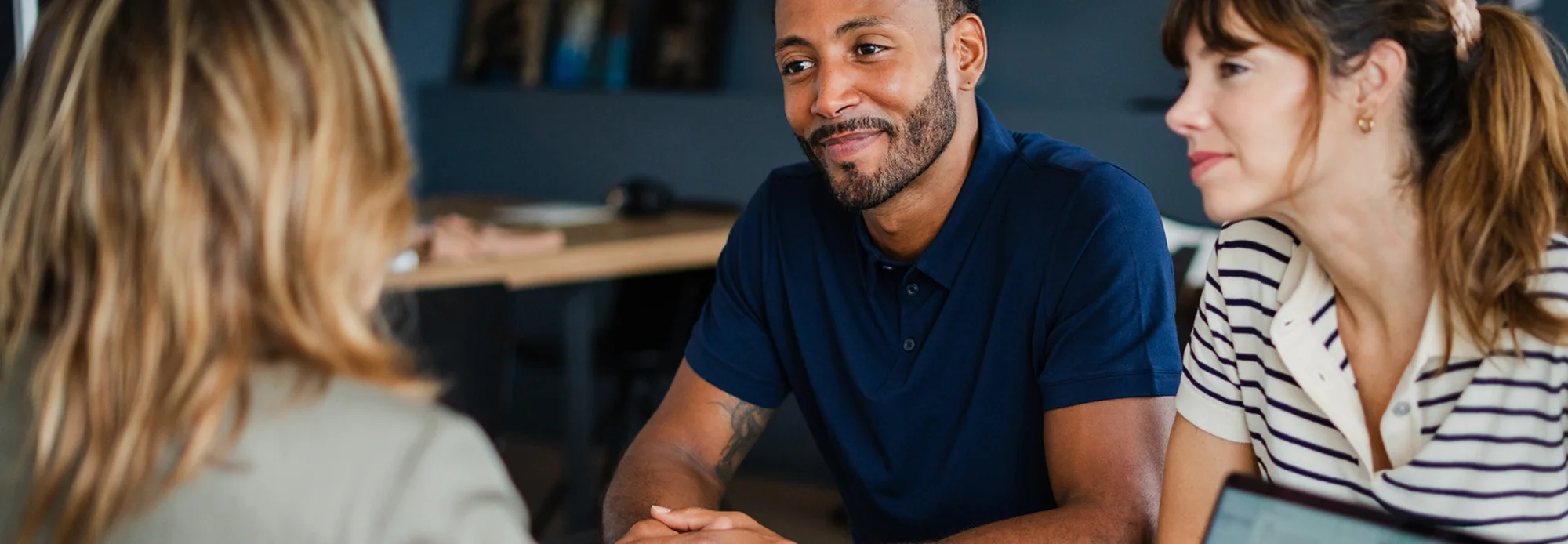 Two homeowners talk with a finance officer and an interpreter about the terms of their loan.
