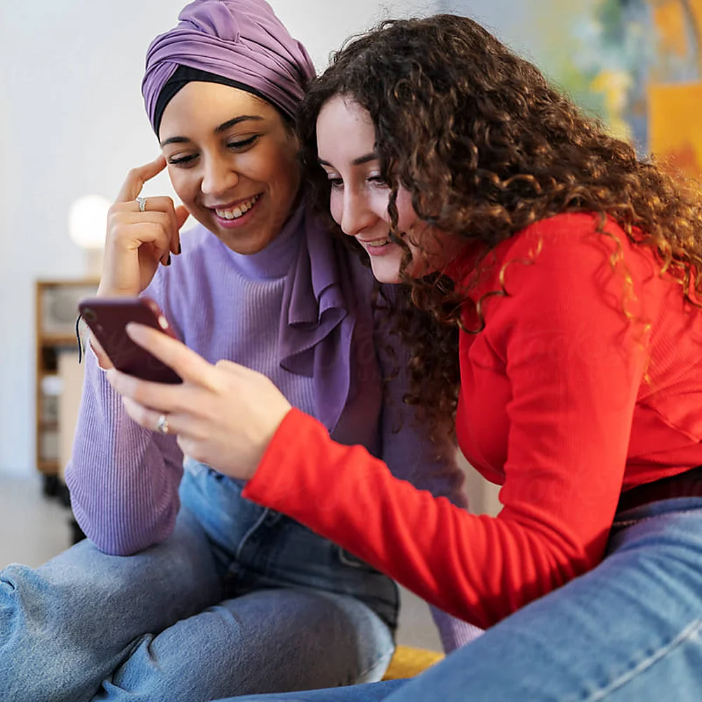 Two friends make a video call on a cell phone together.