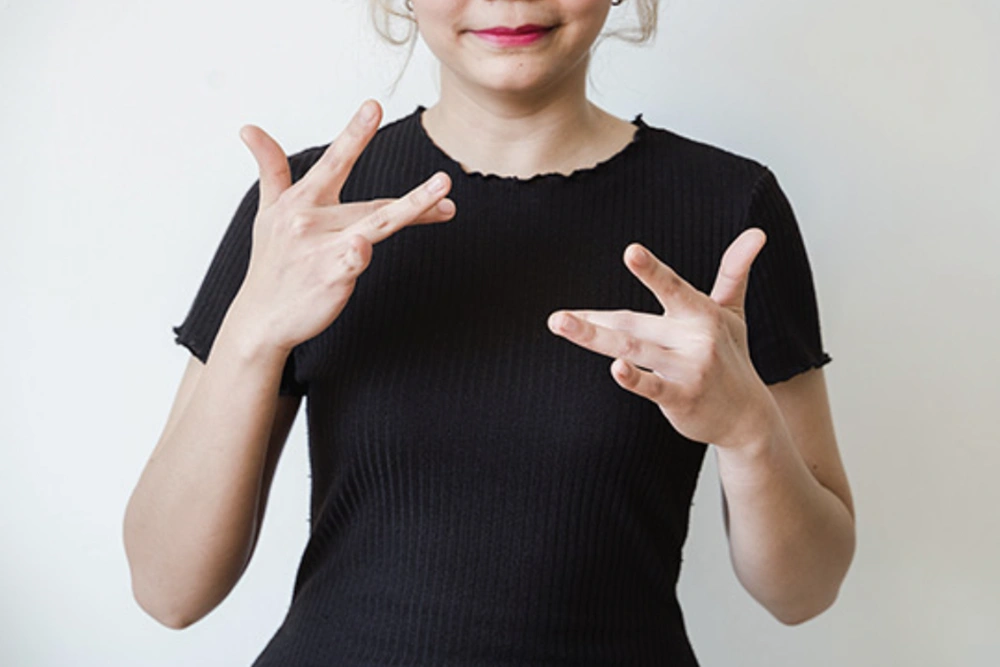 A certified American Sign Language interpreter makes the ASL sign for the word thrilled.