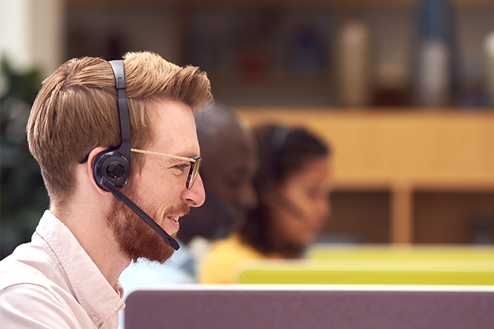 With an interpreter on the line, a healthcare worker wearing a headset calls a patient for a pre-appointment check in.