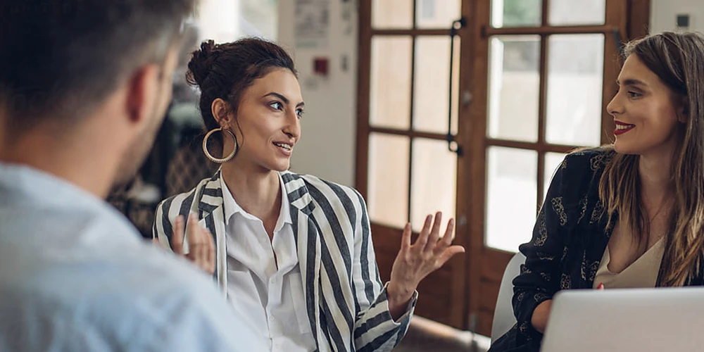 A loan officer meets with an approved client and an interpreter to go over mortgage details in French.