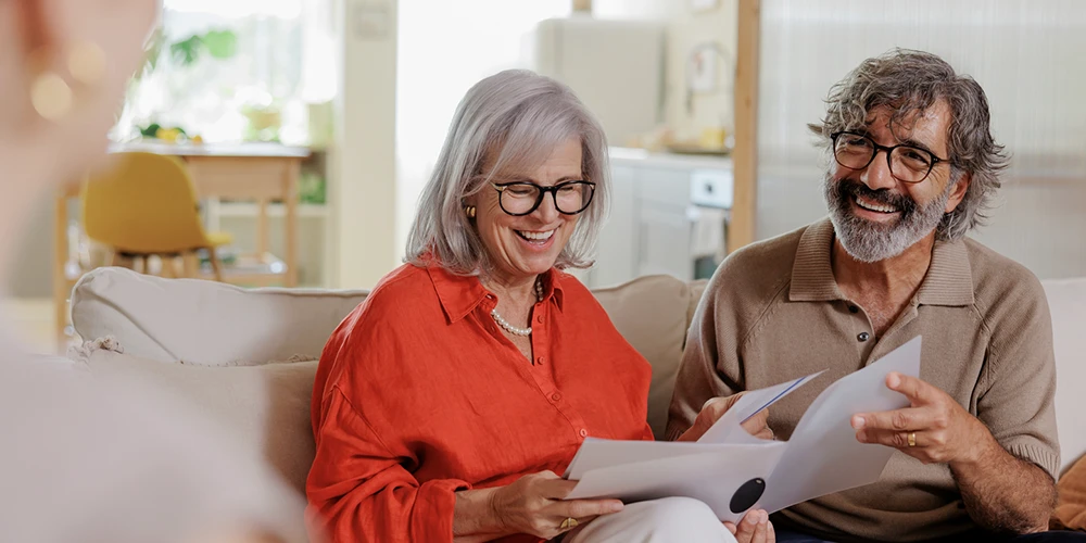 Two home insurance customers smile as they receive translated terms and conditions from their agent.